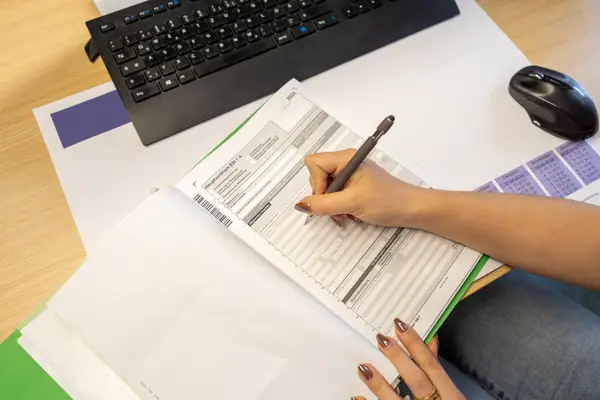 Hand einer Person die einen Steuerbescheid ausfüllt